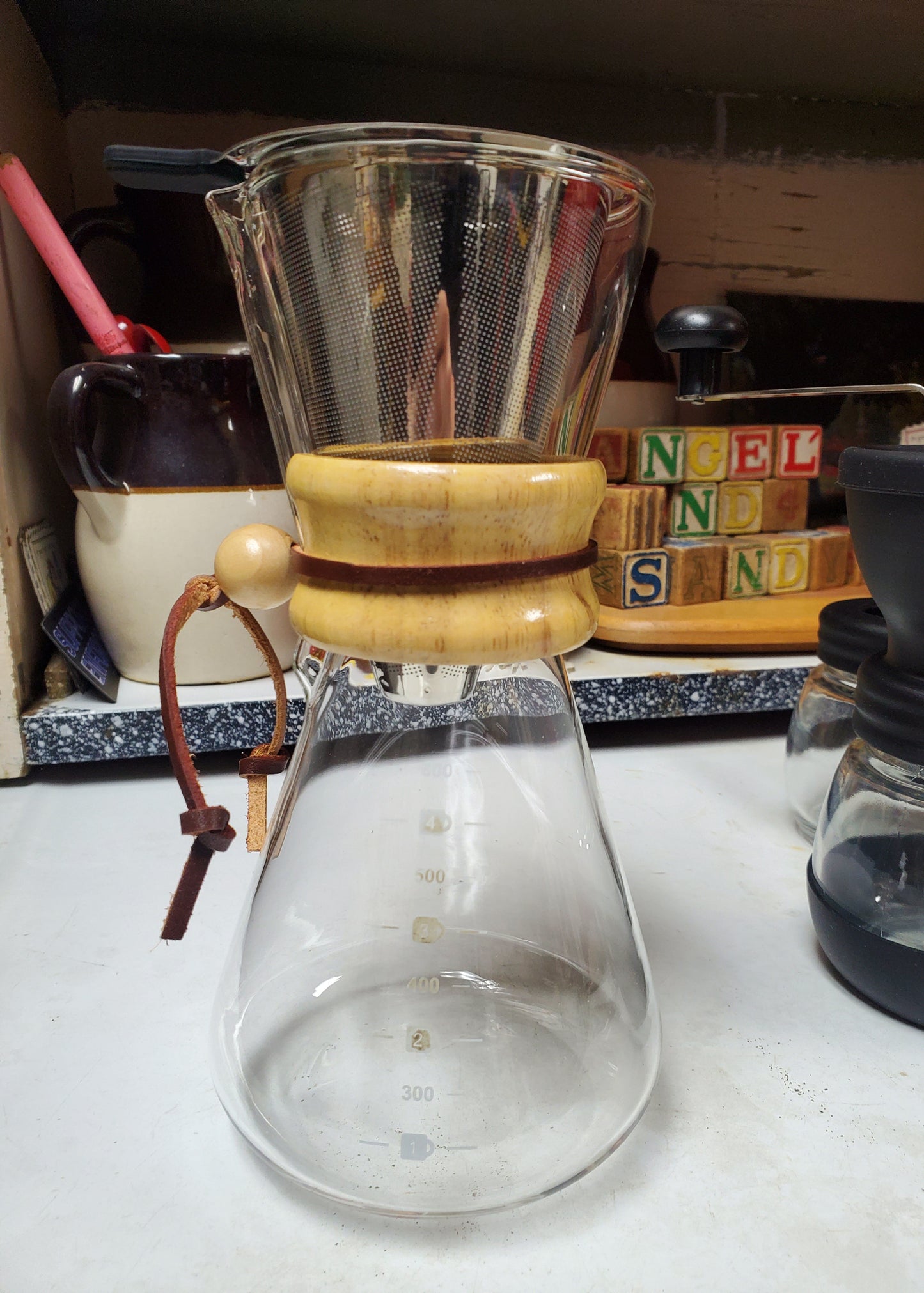 Close-up of a coffee filter with wooden handle on a white surface