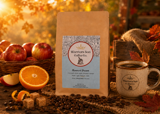 Warriors Son Coffee Co. package with a cup of coffee, apples, and oranges on a wooden table.