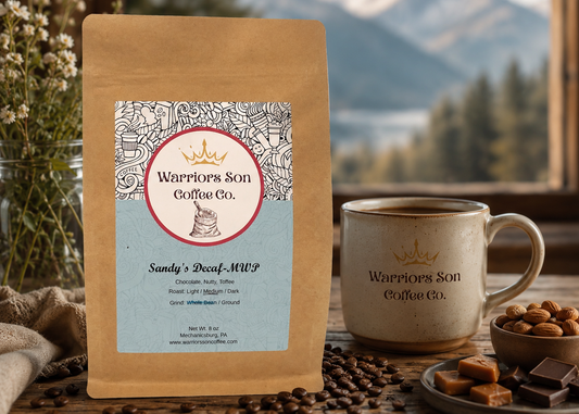 Warriors Son Coffee Co. package with a mug and coffee beans on a wooden table with a mountain view.